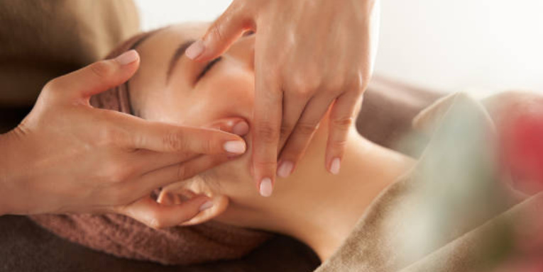 Woman laying on massage table receiving facial massage